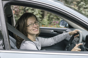 Fototapeta na wymiar Happy young woman driver sits in car. 