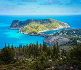 View to Assos village and beautiful blue sea. Cypress trees in foreground. Kefalonia island, Greece