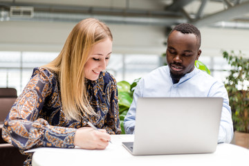 Business woman with African man working on a laptop