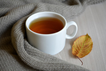 A Cup of hot tea and wool blanket on the table. Autumn or winter warming drink. Autumn concept