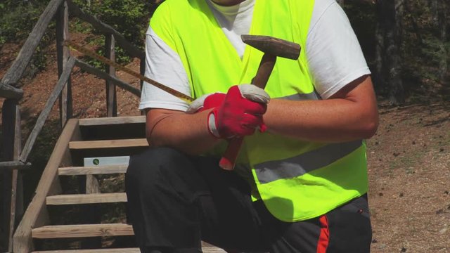 Worker hands with a hammer and a tape measure