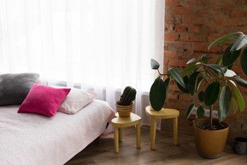 the interior of the bedroom. bedroom with a large bed. bed with pillows. bedside table with flowers. the walls are of brick. large window in the room