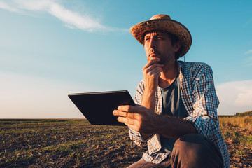 Farmer agronomist with tablet computer in bare empty field
