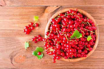 Fresh red currant in a wooden plate on a table. Top view