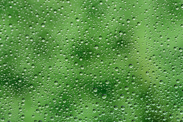 Water drops reflected in a glass against green background.