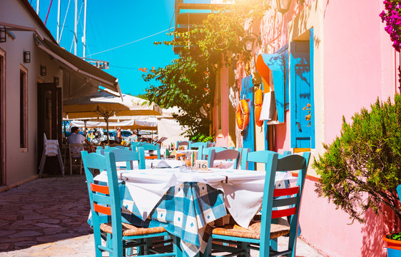 Traditional greek vivid colored tavern on the narrow Mediterranean street on hot summer day