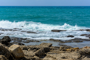 the shore with stone blocks from the ancient city is washed by the waves of the Mediterranean sea