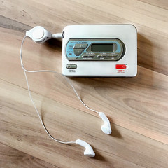 Audio tape player with headphones, gray, lies on wooden background, retro player
