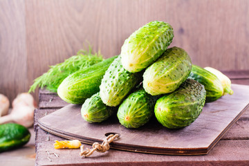 A bunch of fresh cucumbers, dill and garlic on a wooden table