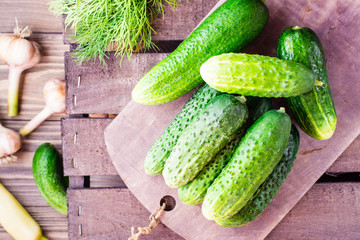 A bunch of fresh cucumbers, dill and garlic on a wooden table. Top view