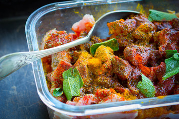 Pickling in herbs and spices of turkey meat in a glass dish.