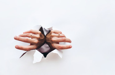 Female hands tear open a hole in white paper. Breaking obstacles. Escape, protest. Copy space for...