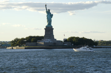 Fototapeta premium Statue of Liberty and a boat crossing the bay, New York