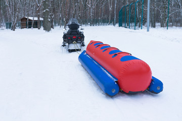 Snowmobile and inflatable sled, winter fun. Winter.