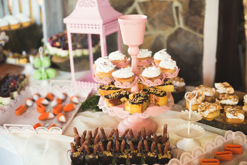 Delicious sweets on wedding candy buffet with desserts, cupcakes