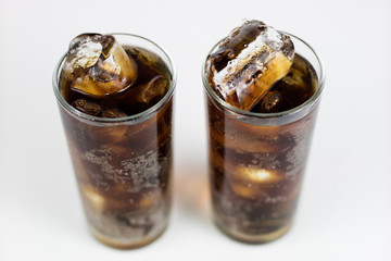 Cold drink with ice in a glass on a white table. A way to cool down on hot days.
