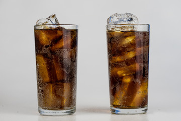 Cold drink with ice in a glass on a white table. A way to cool down on hot days.