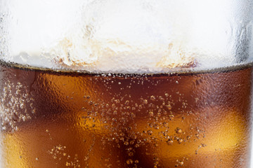 Cold drink with ice in a glass on a white table. A way to cool down on hot days.