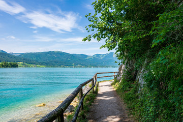 Jetty on the edge of the turquoise lake called Wolfgangsee mountains in the background and clouds on the sky - obrazy, fototapety, plakaty