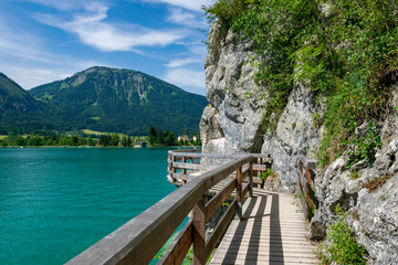 Jetty on the edge of the turquoise lake called Wolfgangsee mountains in the background and clouds on the sky
