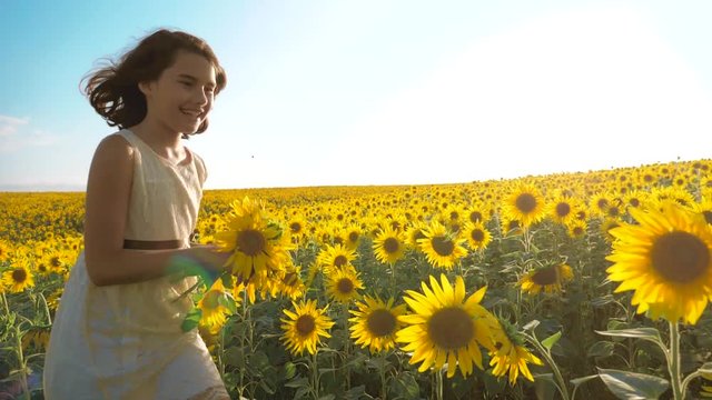 Happy little girl running happy free across the field with sunflowers. slow motion video lifestyle. smelling big sunflower on summer field. Delight of a pleasant smell. Summer holiday. concept