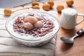 Close up soft sweet purple sticky rice pudding, Black Glutinous Rice, with longan and coconut cream on wooden table