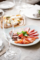 Food tray with delicious salami, pieces of sliced ham, sausage. Cutting sausage and cured meat on a celebratory table.
