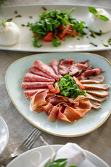 Food tray with delicious salami, pieces of sliced ham, sausage. Cutting sausage and cured meat on a celebratory table.