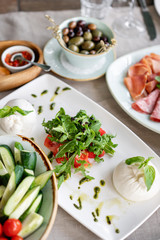 Italian Caprese salad. burrata cheese, tomatoes and basil herb leaves. Balsamic vinegar arranged on white plate