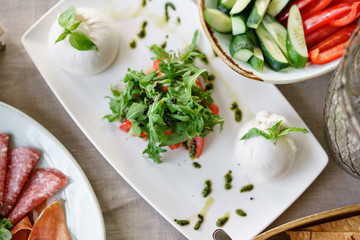 Italian Caprese salad. burrata cheese, tomatoes and basil herb leaves. Balsamic vinegar arranged on white plate