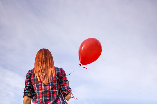 Rear View Of Girl With Red Balloon Against The Sky.