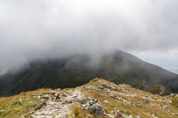 Fototapeta premium mountain ridge covered by half with the cloud