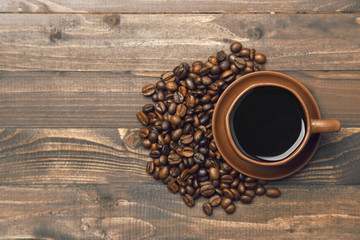 A cup of coffee and coffee beans on a wooden background, top view.