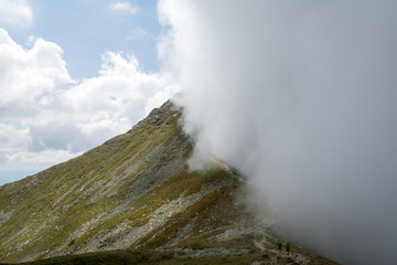 mountain ridge covered by half with the cloud