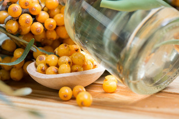 Sea-buckthorn oil and berries buckthorn branch in bowl on a wooden background. selective focus image 