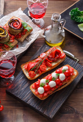Bruschetta with tomato, basil and mozzarella cheese on wooden board. Traditional italian appetizer or snack, antipasto