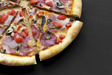 Freshly baked pizza on black background, closeup.