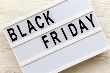 'Black Friday' word on lightbox over white wooden background, top view. Flat lay, overhead, from above.