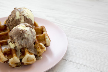 Traditional belgian waffle with icecream on pink plate over white wooden background, side view. Closeup. Copy space.