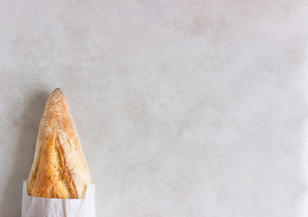 Fresh baguette in a paper bag on the white background. Top view, copy space.