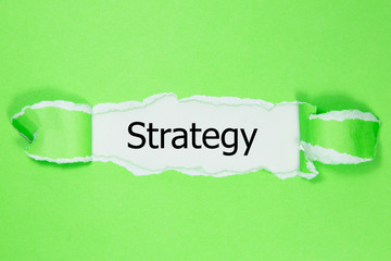 The word strategy appearing behind torn paper.