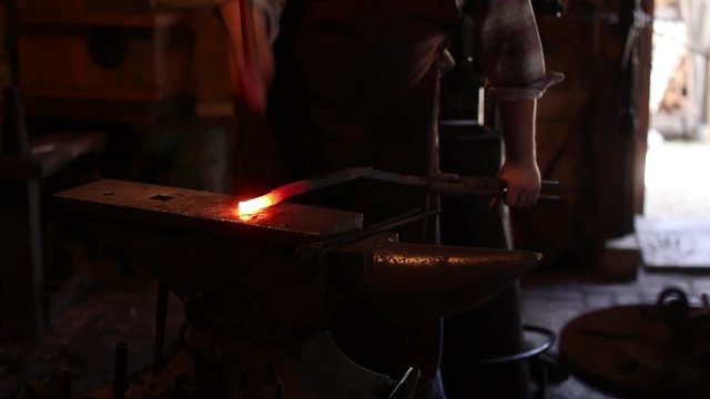 Blacksmith hammering a red hot piece of metal on an anvil