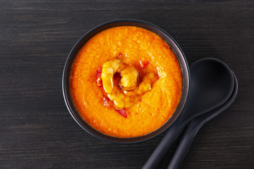 Soup gazpacho with shrimps, Italian cuisine. Plate with soup in a black plate on a black background. Top of the Vieux. Copyspace.