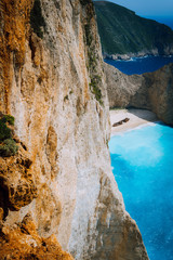 Limestone chalk huge cliff rocks and Navagio beach with abandoned Shipwreck in the distance. Azure blue colored sea. Zakynthos island, Greece