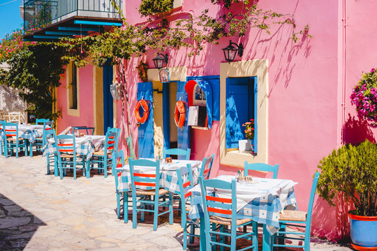 Fototapeta Traditional greek vivid lilac colored tavern on the narrow Mediterranean street on hot summer day