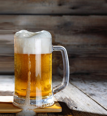 Mug of light beer on a wooden table, rustic style