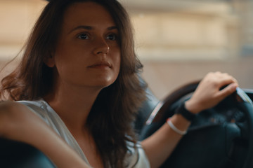 Close-up portrait of woman holding hand on steering wheel