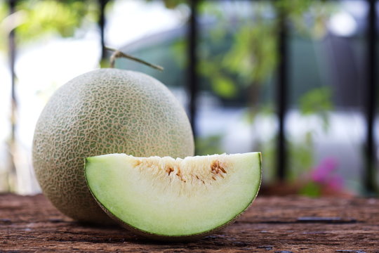 Slice of sweet green melon on wooden table.