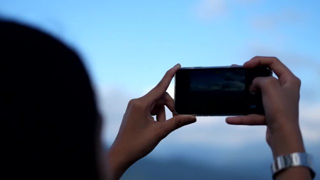 A female tourist taking pictures of the beautiful scenery from the top of a mountain in Mines View Park in Baguio, Philippines.