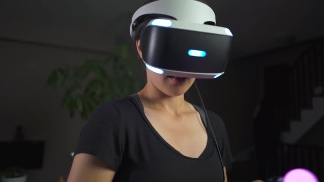 Woman playing Virtual Reality in living room and laughing